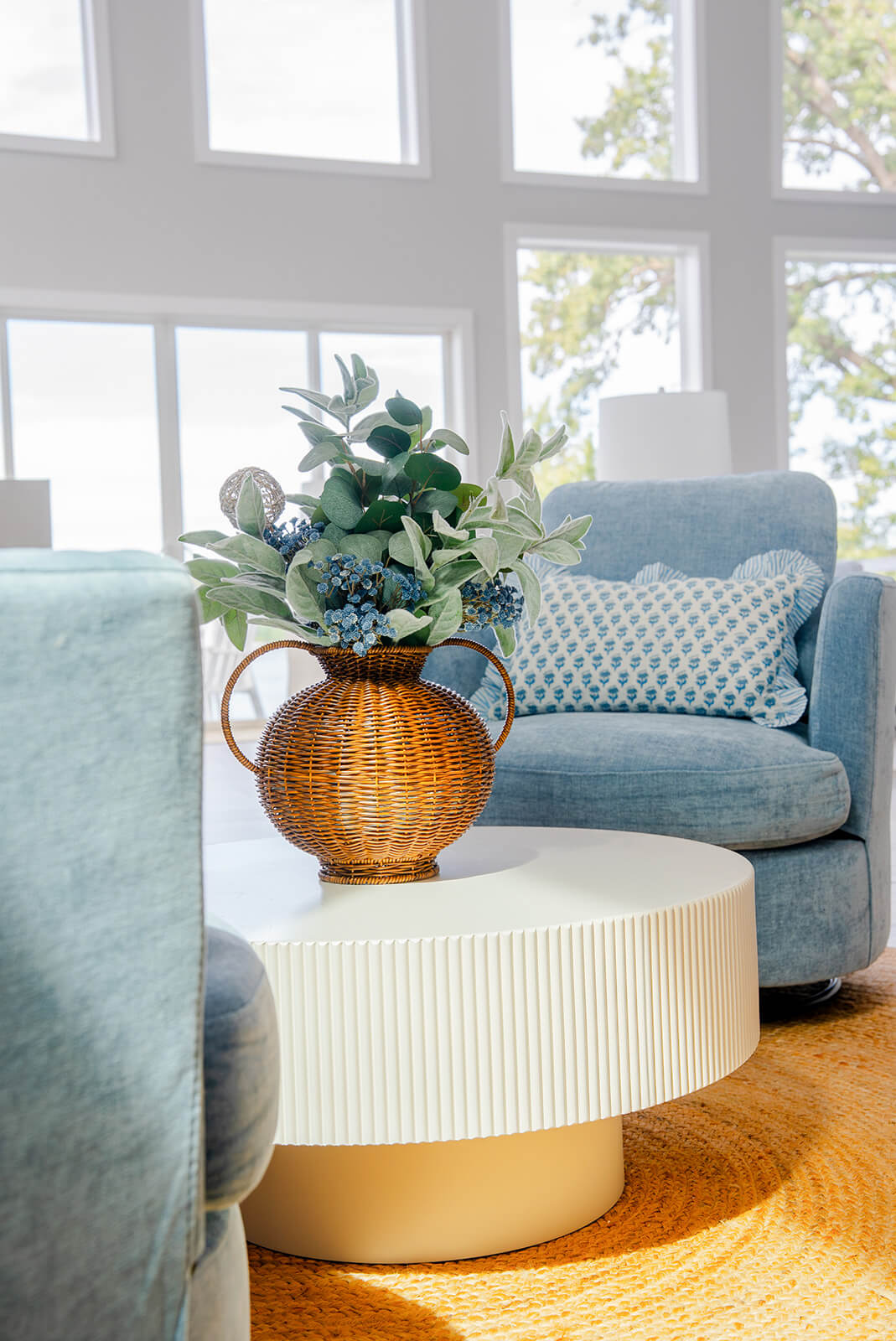 Okoboji-Lake-House-16 Living area with blue patterned accent chairs, lush greenery, and layered coastal-inspired interior design