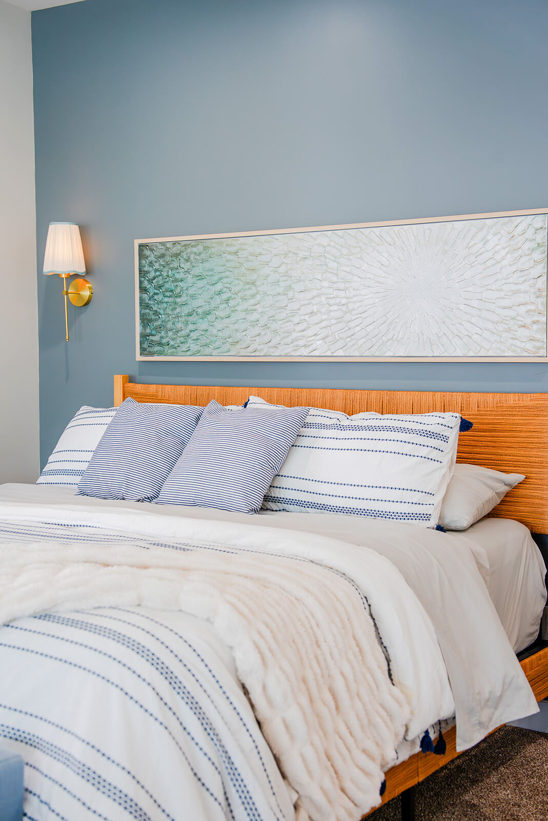 Okoboji-Lake-House-21 Serene Okoboji Lake House bedroom with a blue accent wall, natural wood headboard, and relaxed design