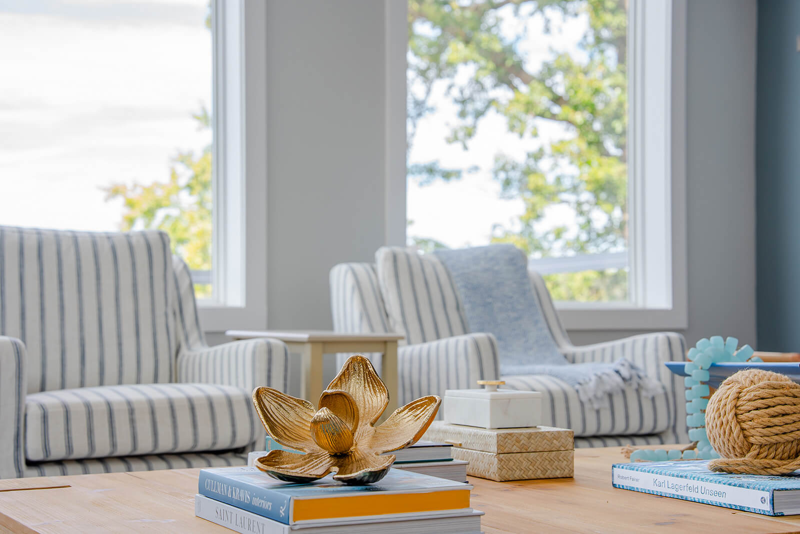 Okoboji-Lake-House-6 Airy sitting area with striped accent chairs, large windows, and gold decorative accents