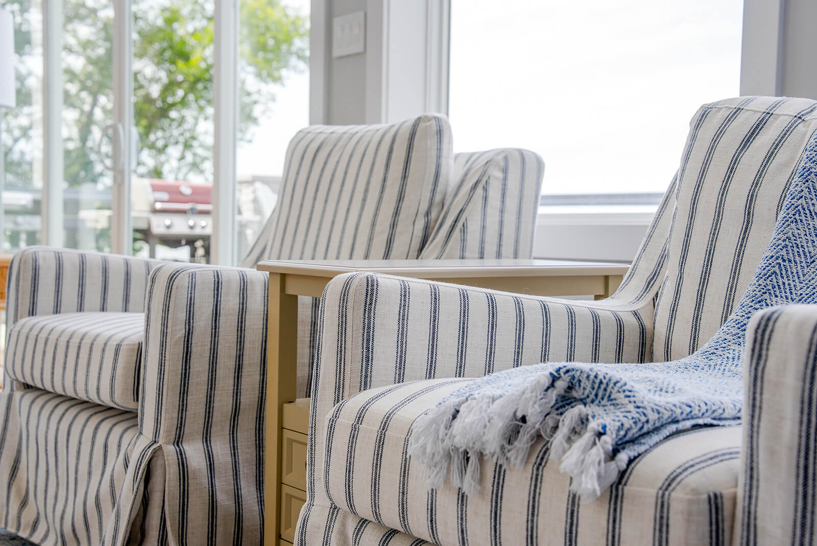 Okoboji-Lake-House-7 Cozy sitting area with striped chairs, soft textiles, natural light, and understated decor