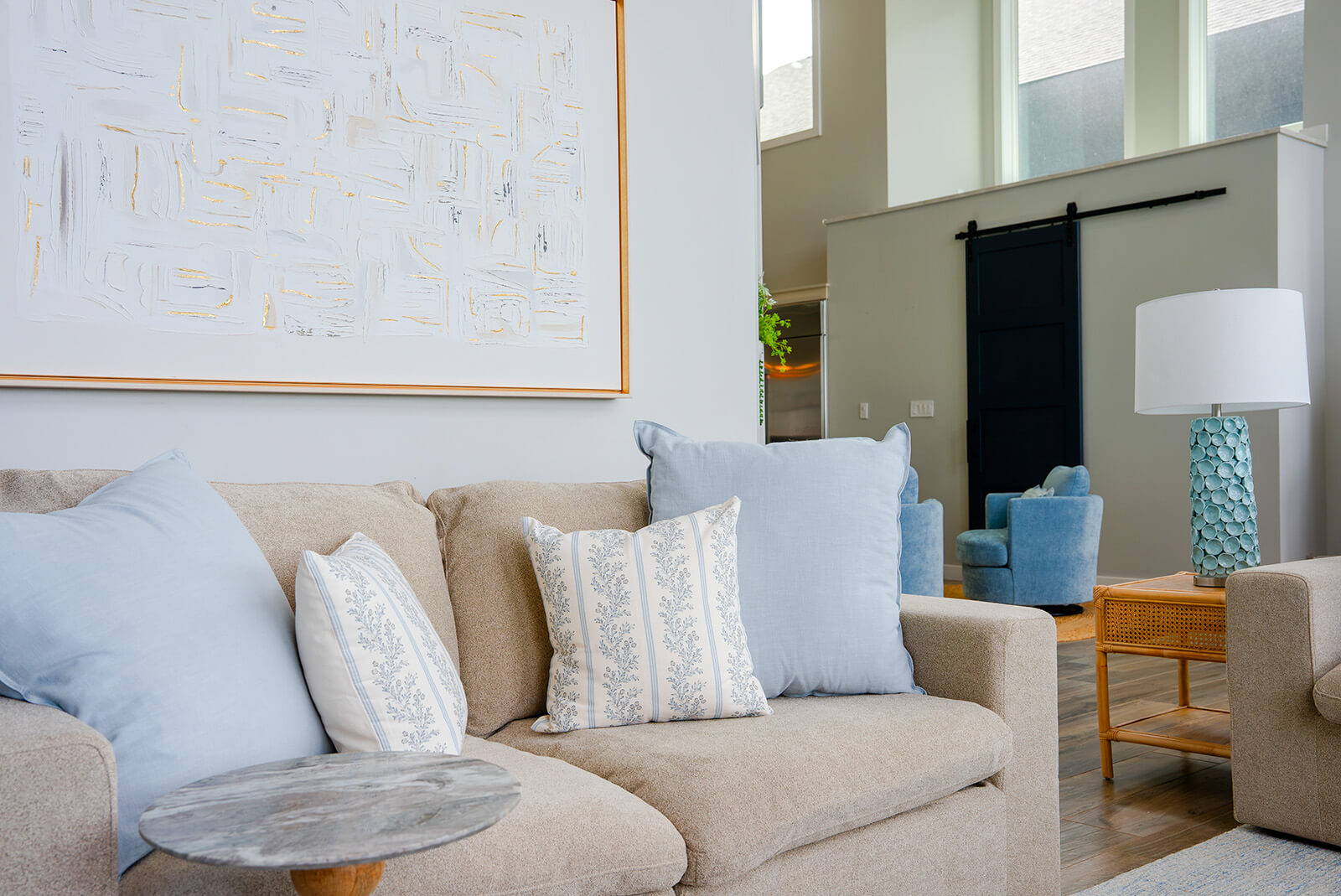 Okoboji-Lake-House-8 Serene costal-inspired living room with sand colored couch, natural wood accents, and oversized wall art