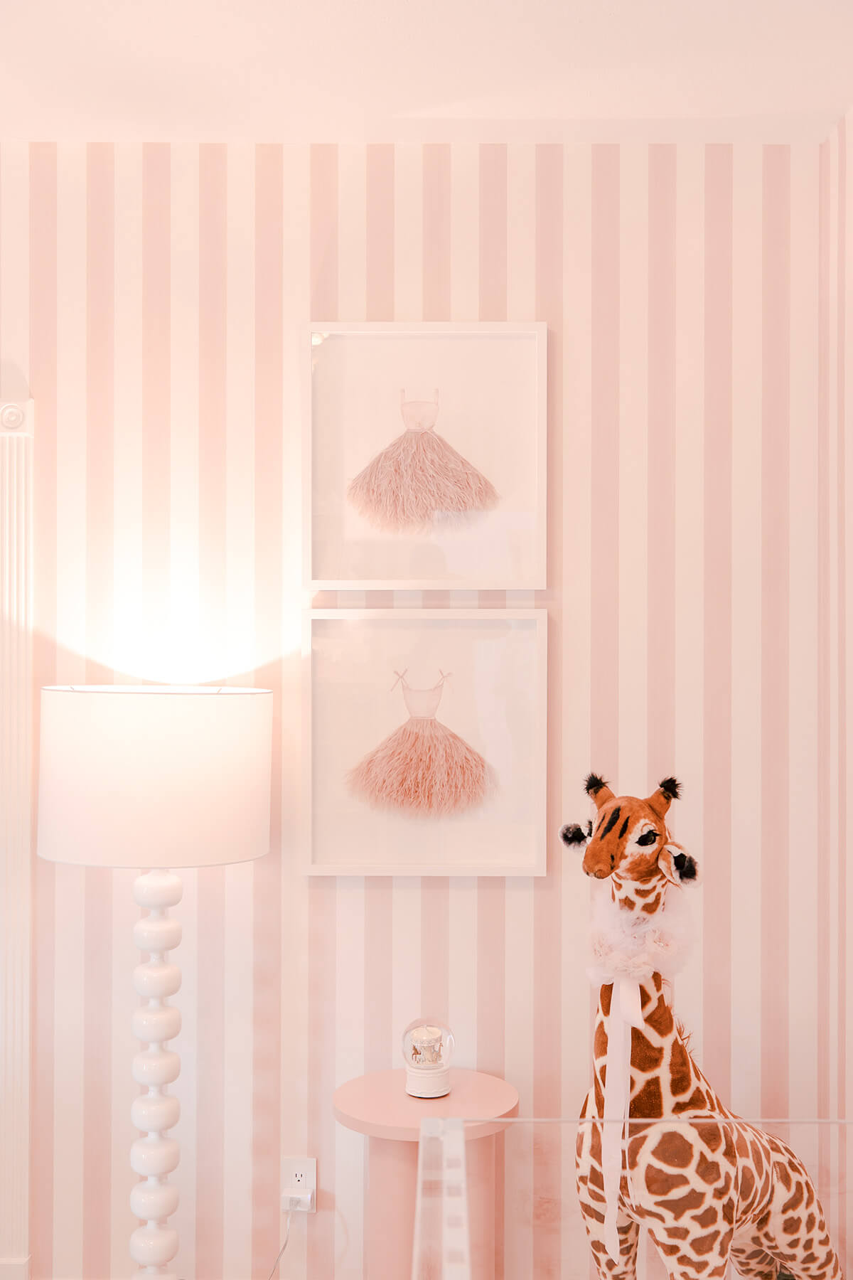 Storybook-20 Whimsical nursery wall featuring pink stripes, delicate artwork, and playful animal-inspired decor