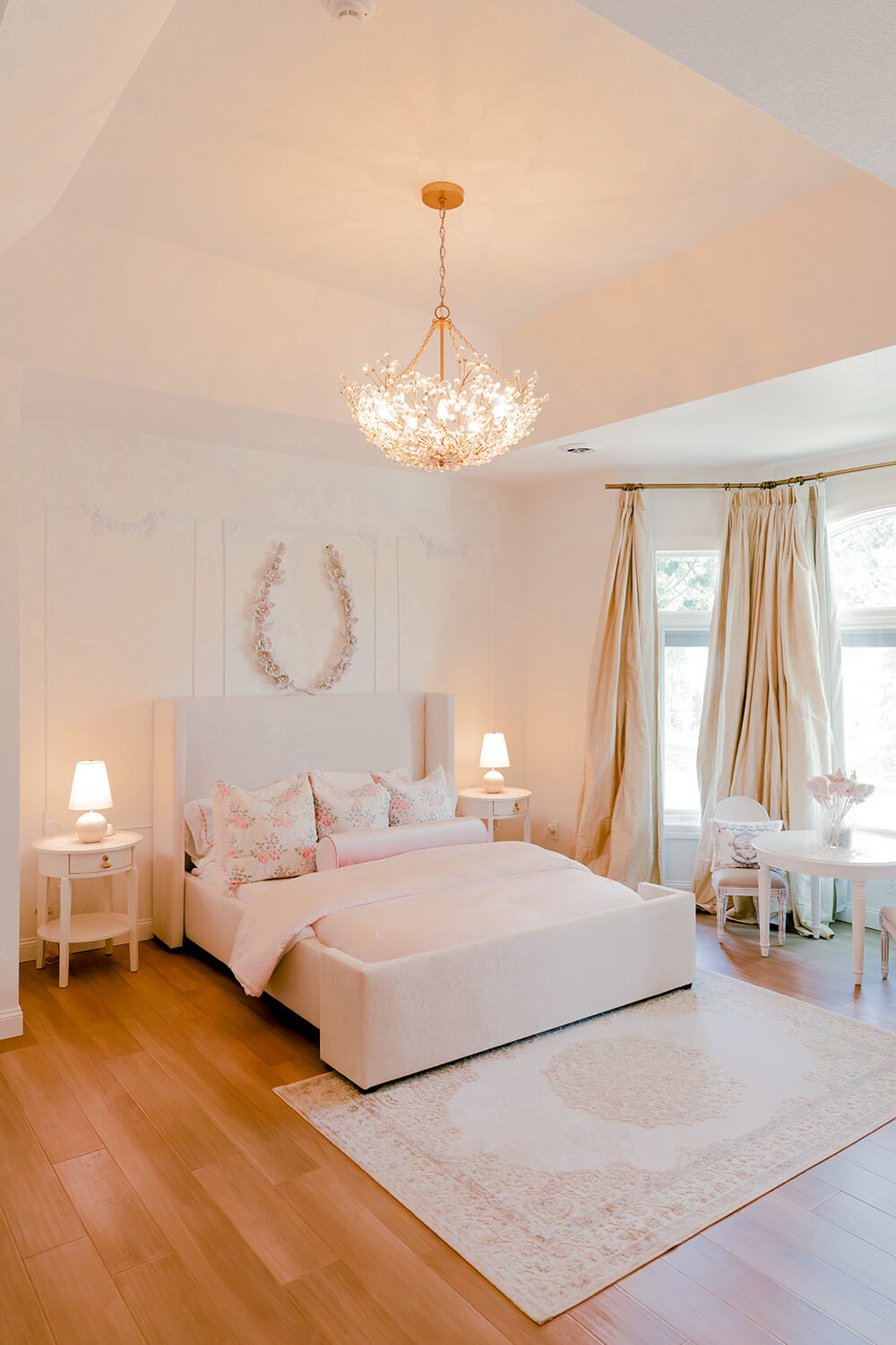 Storybook-29 Serene bedroom layered with soft pink textiles, floral pillows, warm lighting, and elegant window treatments
