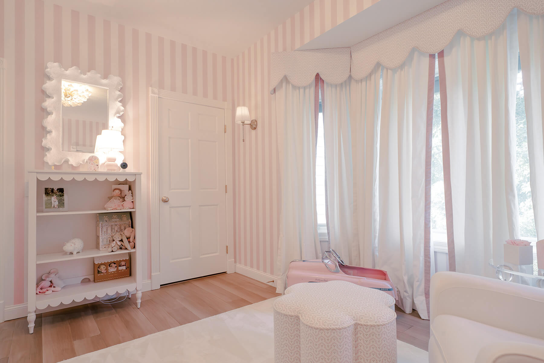 Storybook-5 Elegant nursery with pink striped walls, white furnishings, layered textiles, and delicate decorative details