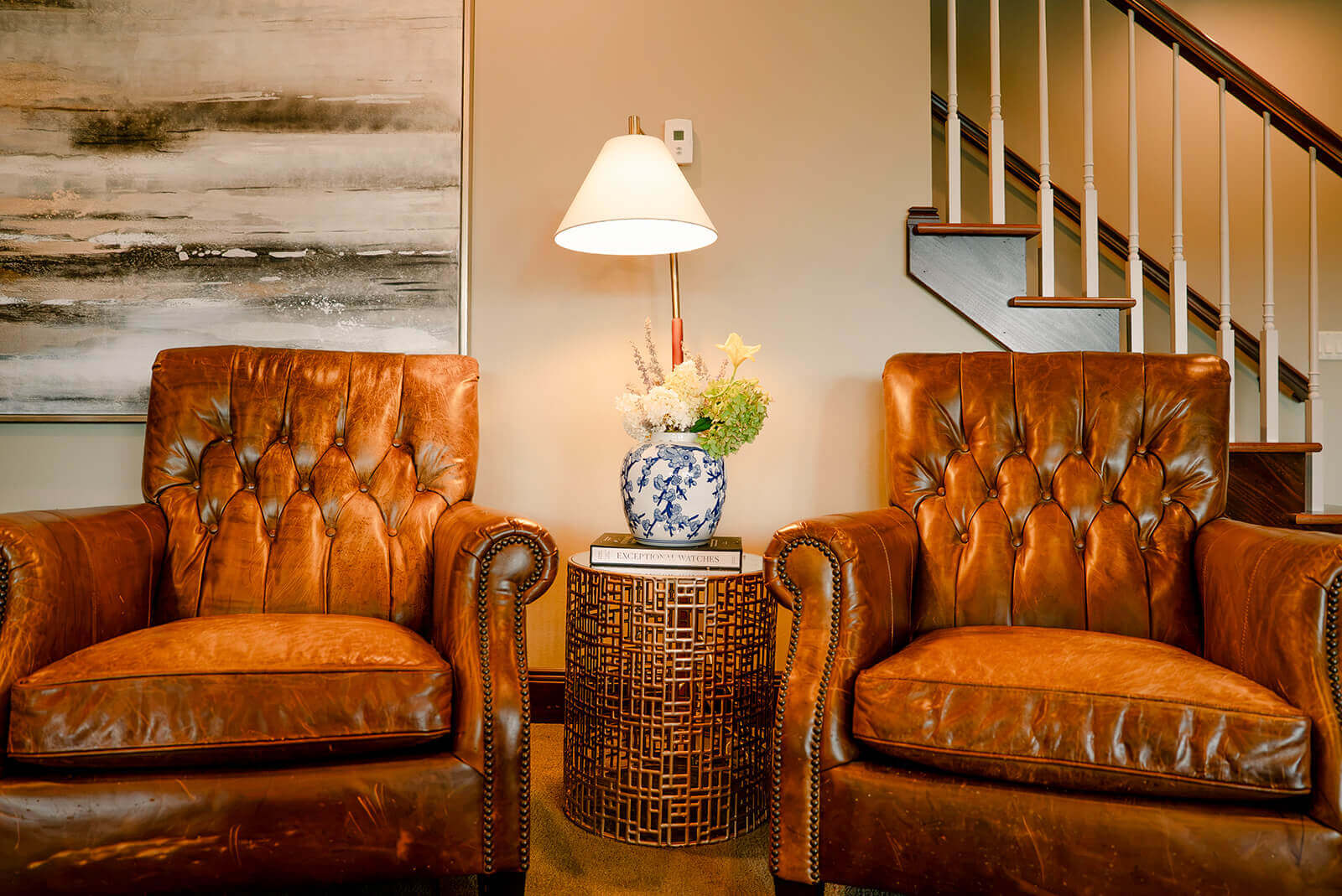 taylor-jane-project-14 Rich leather seating creates a warm, inviting atmosphere beside a softly lit staircase