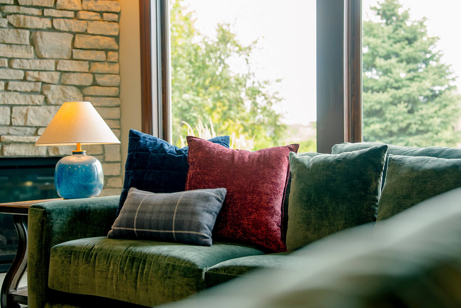 taylor-jane-project-16 Cozy living room with deep green sofa, colorful pillows, and expansive views through large windows