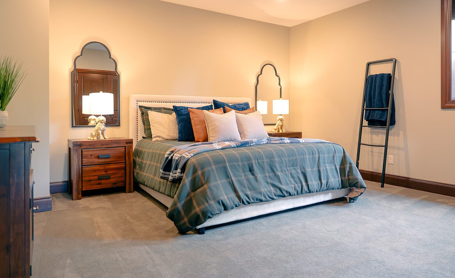 taylor-jane-project-21 Inviting bedroom with blue-and-white bedding, layered pillows, warm wood furnishings, and soft ambient lighting