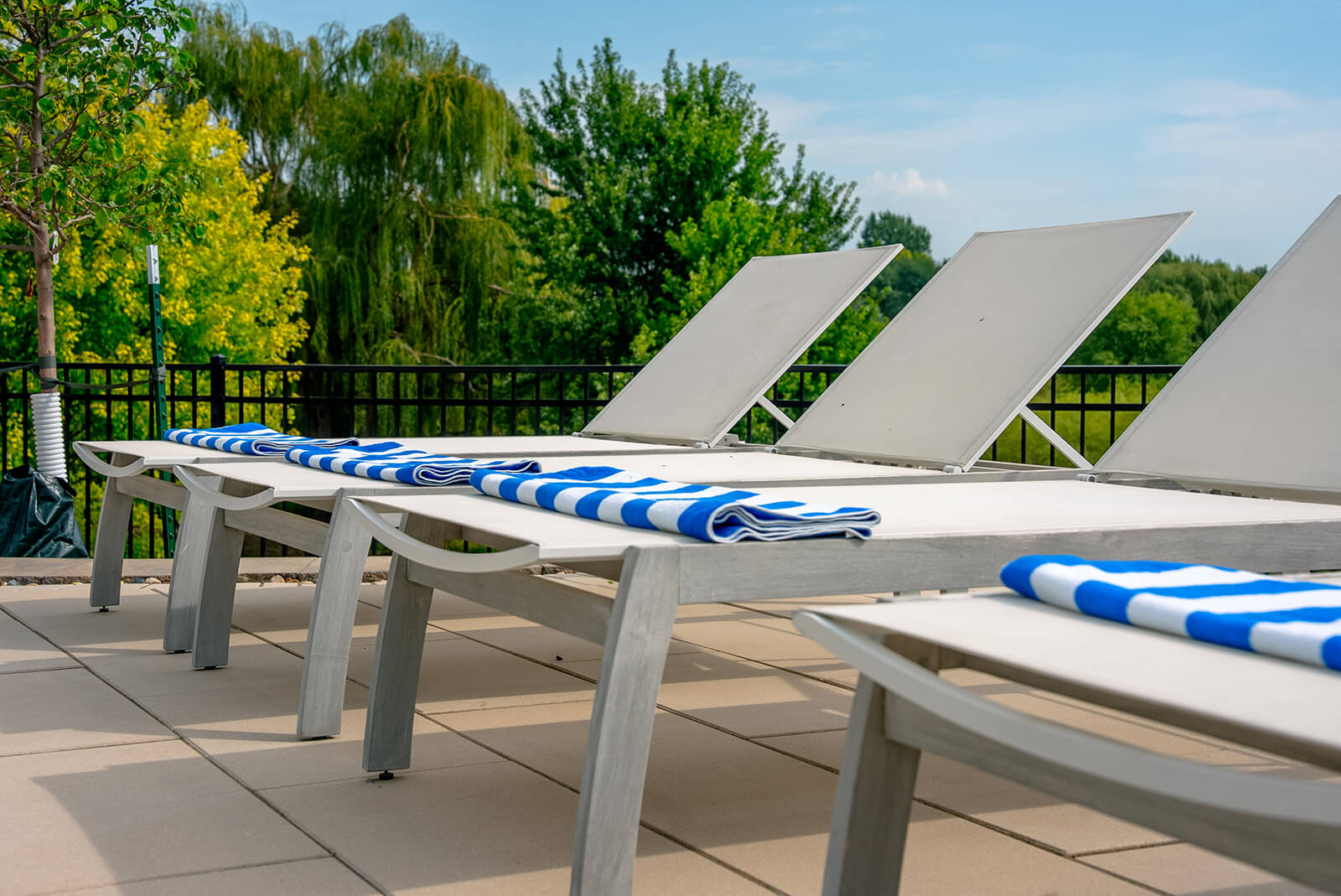 taylor-jane-project-25 Poolside retreat with white loungers, blue-and-white striped cushions, and a lush green landscape beyond