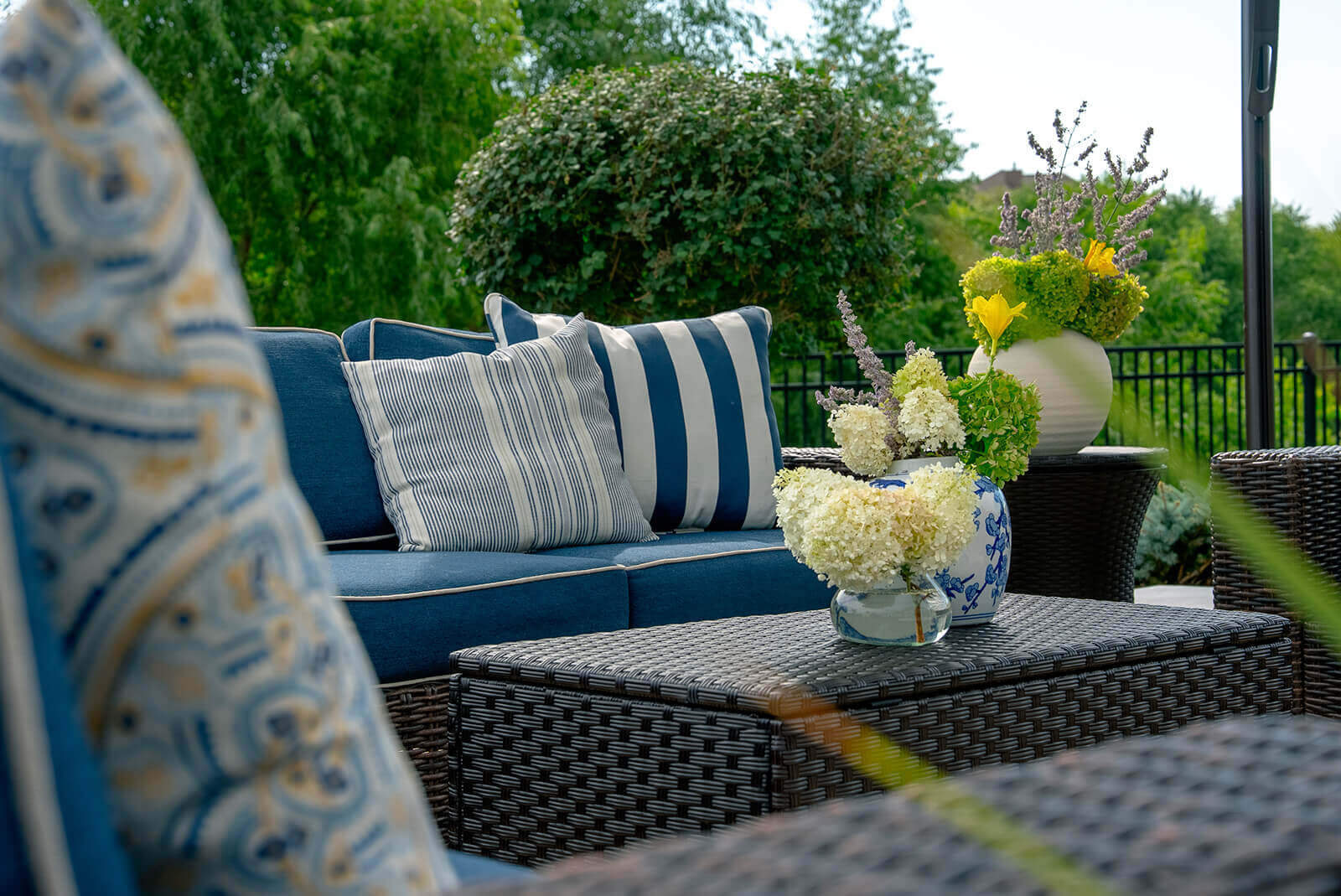 taylor-jane-project-26 Inviting outdoor lounge with deep blue cushions, striped pillows, fresh florals, and lush greenery