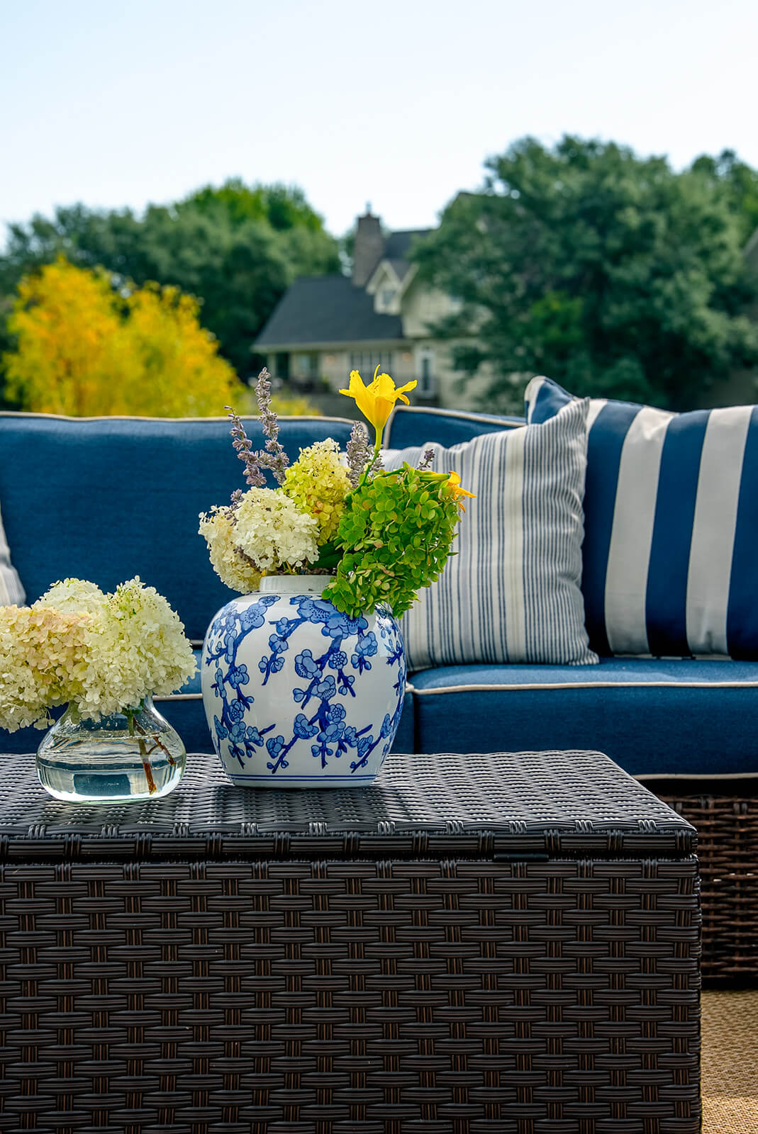 taylor-jane-project-28 Refined outdoor sofa styled with blue-and-white striped pillows and fresh hydrangeas in a blue floral vase
