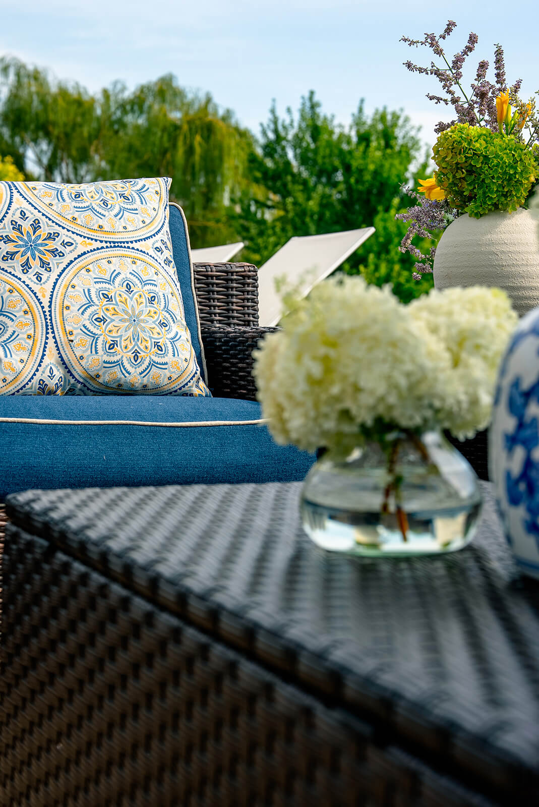 taylor-jane-project-29 Close-up of blue outdoor seating with patterned pillows, fresh hydrangeas, and layered garden views