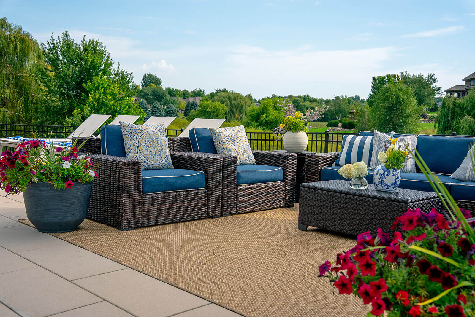 taylor-jane-project-30 Elegant outdoor living area with deep blue seating, patterned pillows, and lush landscaping surrounding the patio