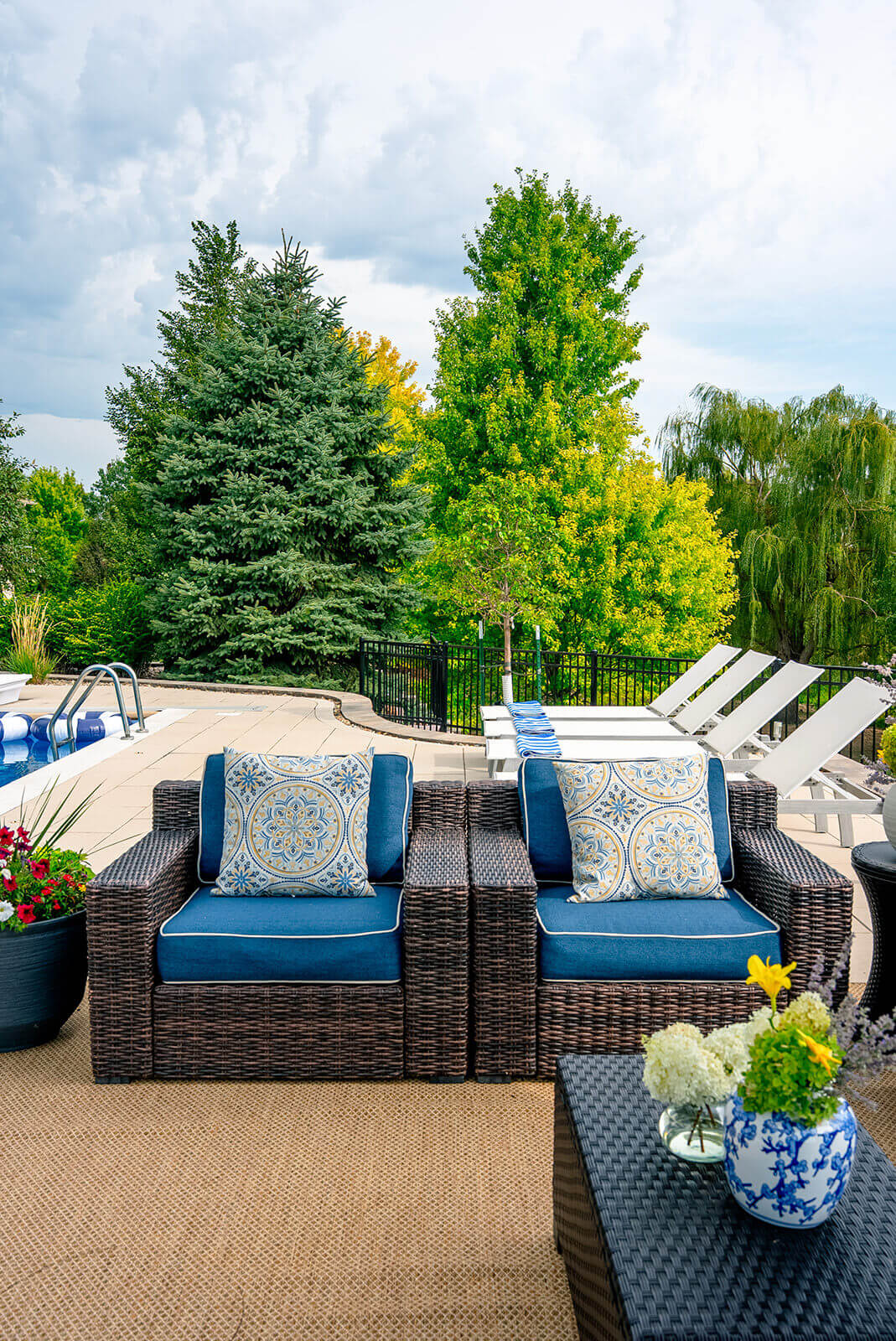 taylor-jane-project-32 Bright poolside seating area with blue-and-white cushions, striped textiles, and lush green landscaping