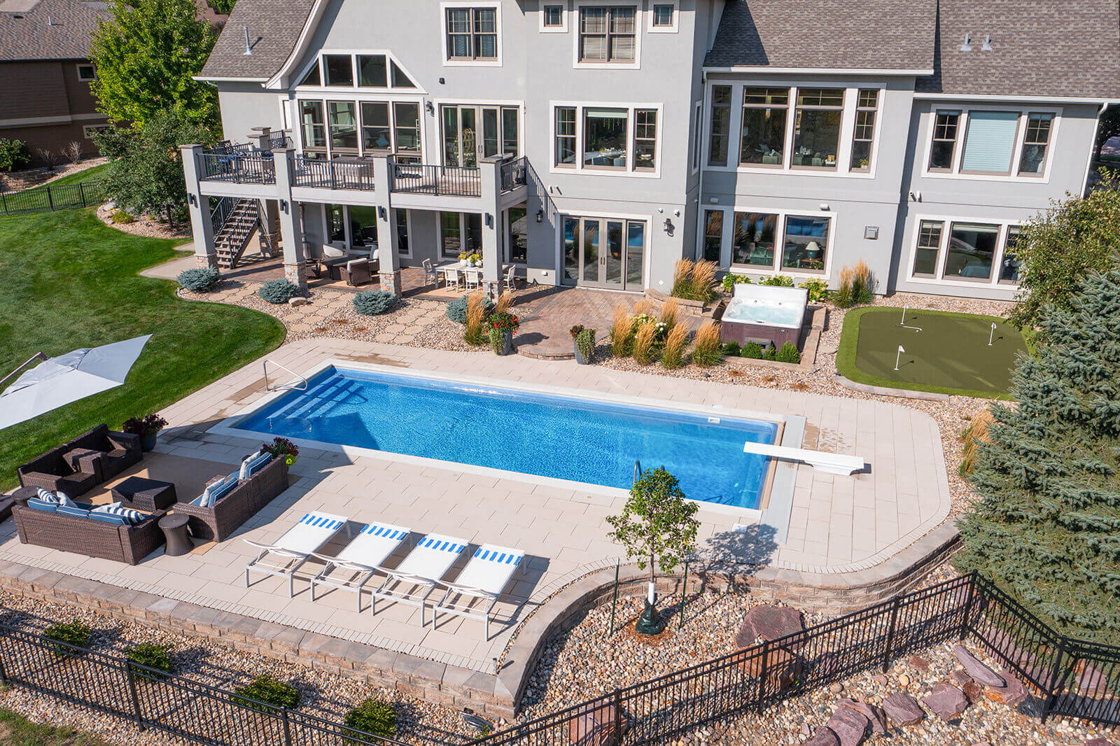 taylor-jane-project-36 Expansive backyard with a blue swimming pool, surrounding patio, and elegant white home framed by lush landscaping