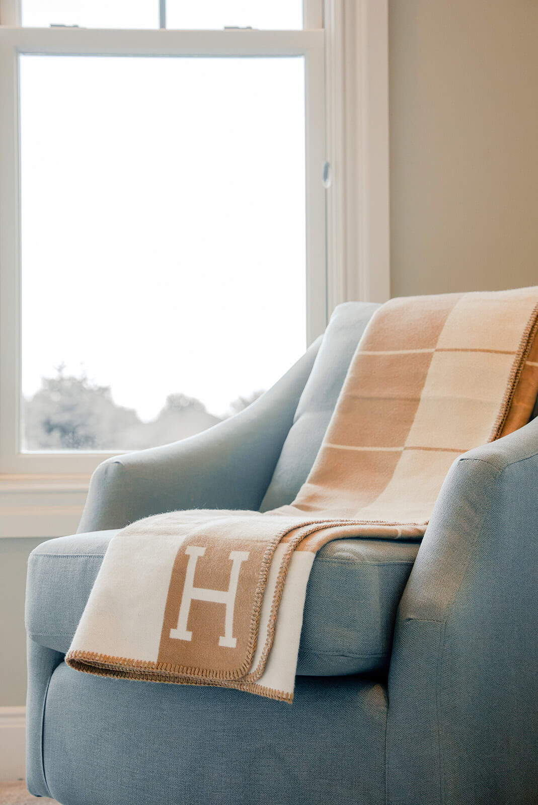taylor-jane-project-5 Plush upholstered chair with a soft neutral throw overlooking bright outdoor views