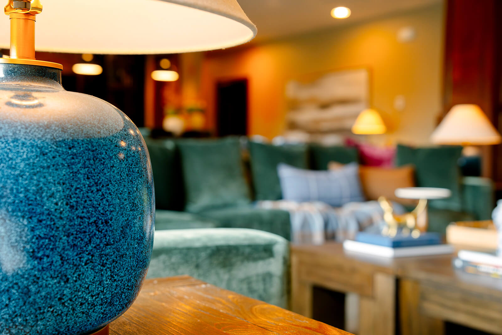 taylor-jane-project-8 Blue speckled lamp glowing softly in front of a cozy living room with layered textures and warm furnishings