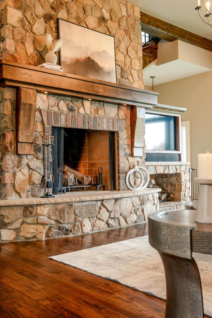 the-hearth-project-3 Refined living room with stone fireplace, leather chair, wood beams, and warm natural textures