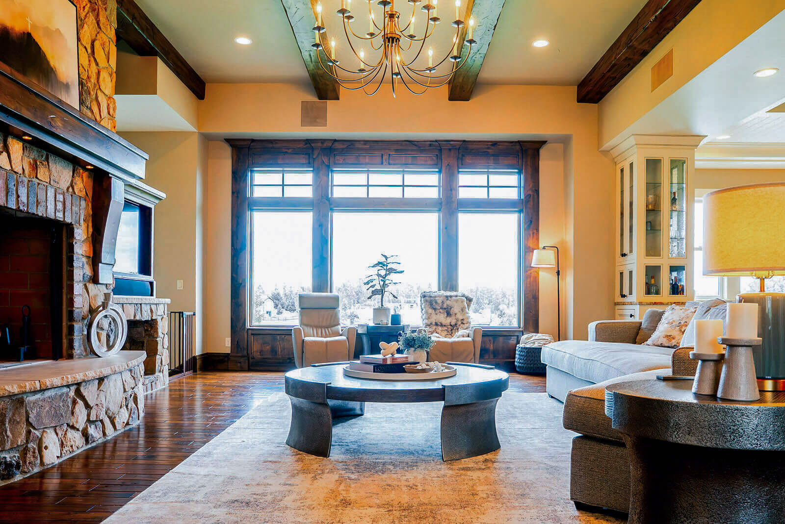 the-hearth-project-9 Inviting living room with large windows, warm wood beams, and layered neutral furnishings