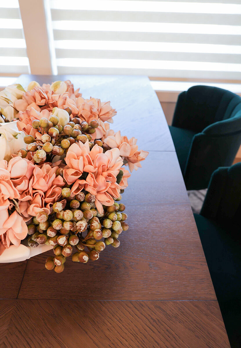 companion-project-7 Close-up of a floral arrangement with pink and peach flowers on a dining table