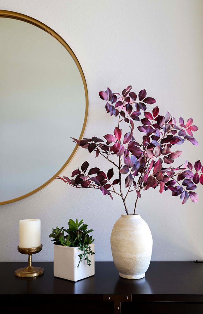 companion-project-8 Decorative console vignette with a round mirror, floral arrangement, and ceramic vase