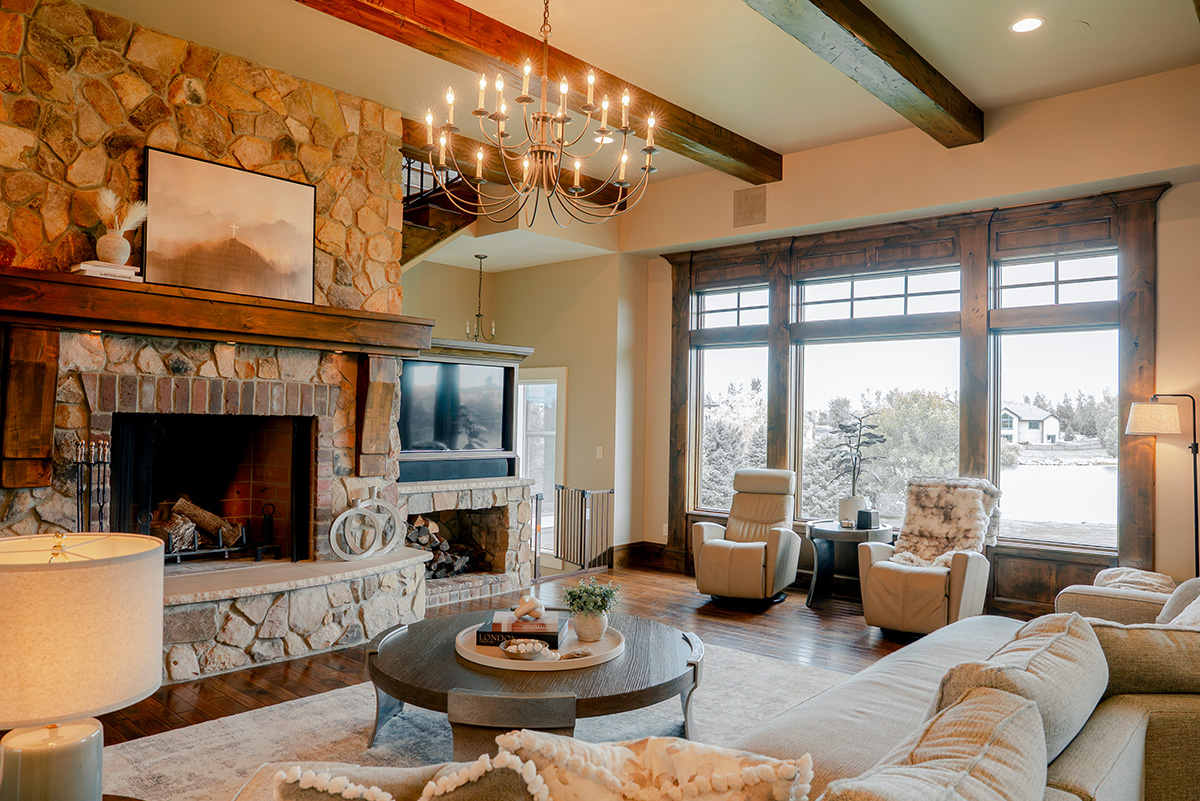 hearth-project-add-5 Spacious living room with stone fireplace, exposed beams, and light-colored furnishings