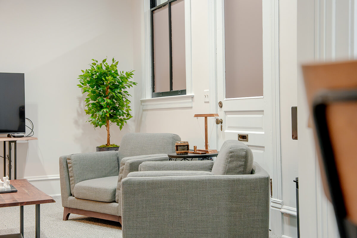 principle-properties-project-10 Modern office lounge with gray seating, white cabinetry, and natural wood accents