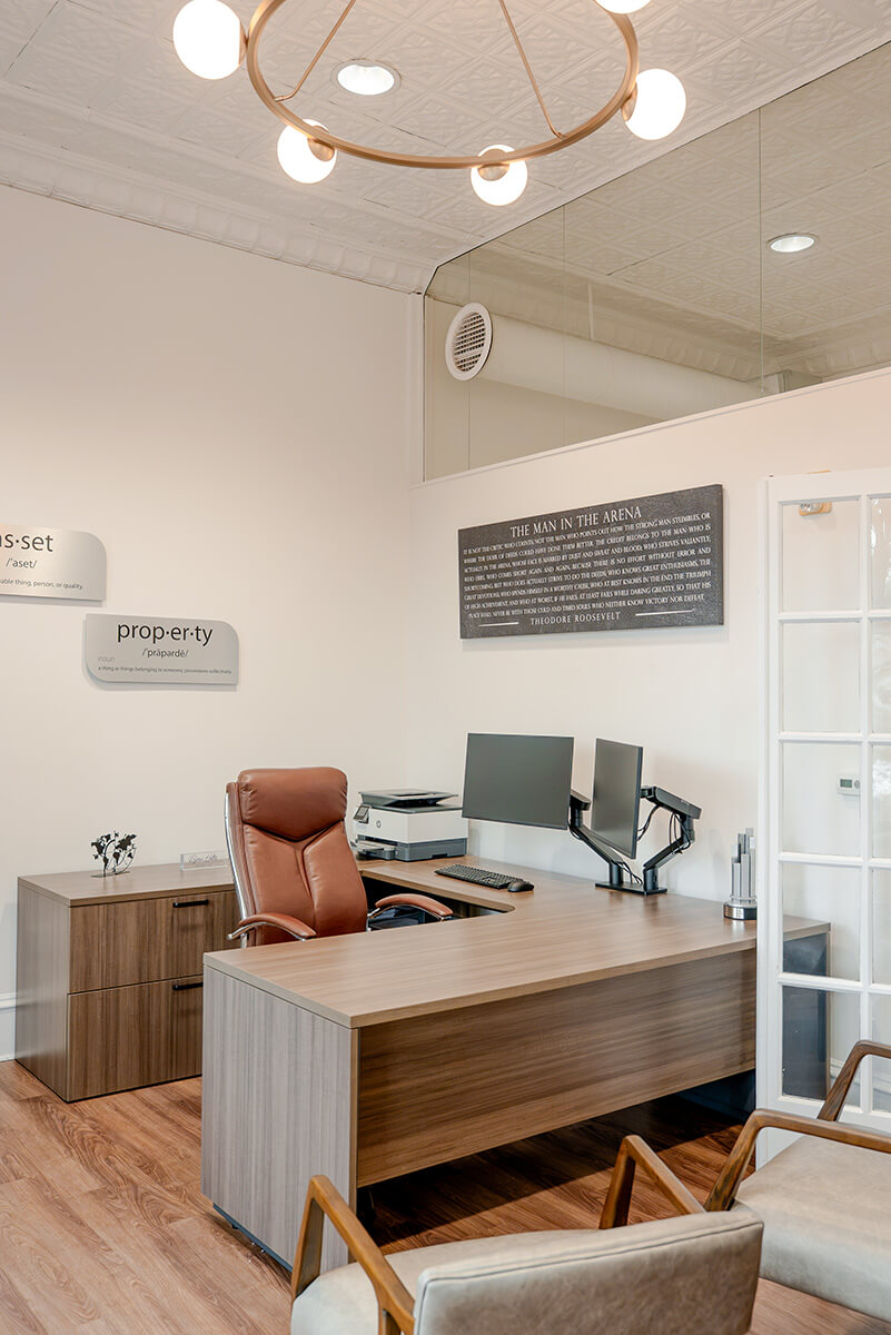 principle-properties-project-5 Bright office lounge with a wood desk, seating area, and glass-front cabinetry