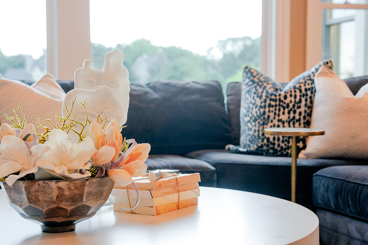 taylor-jane-project-53 Navy sectional with patterned pillows and floral centerpiece in a bright living room